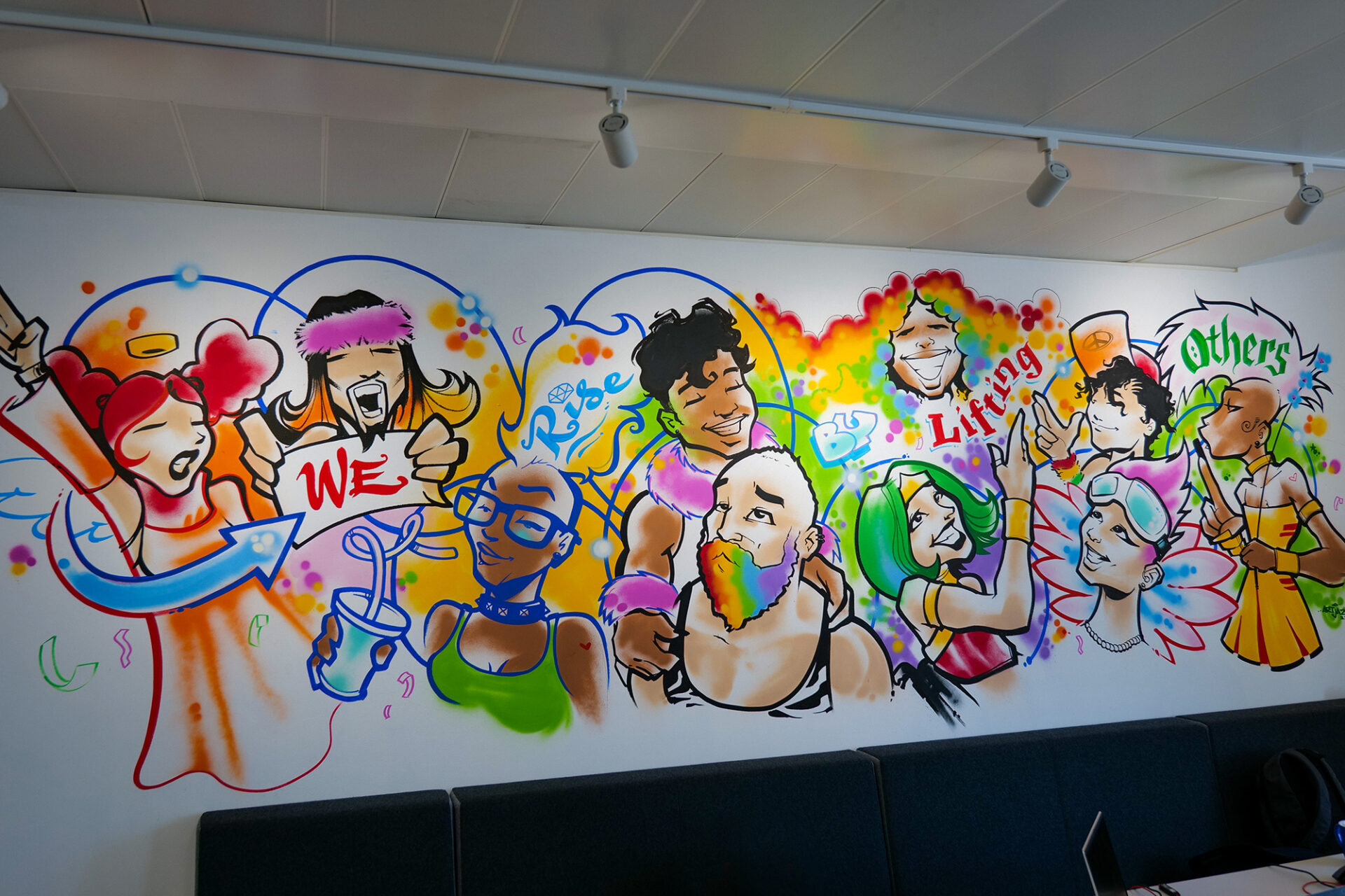 Colourful graffiti mural in the7stars Reception area of various people with text saying "We rise by lifting others"