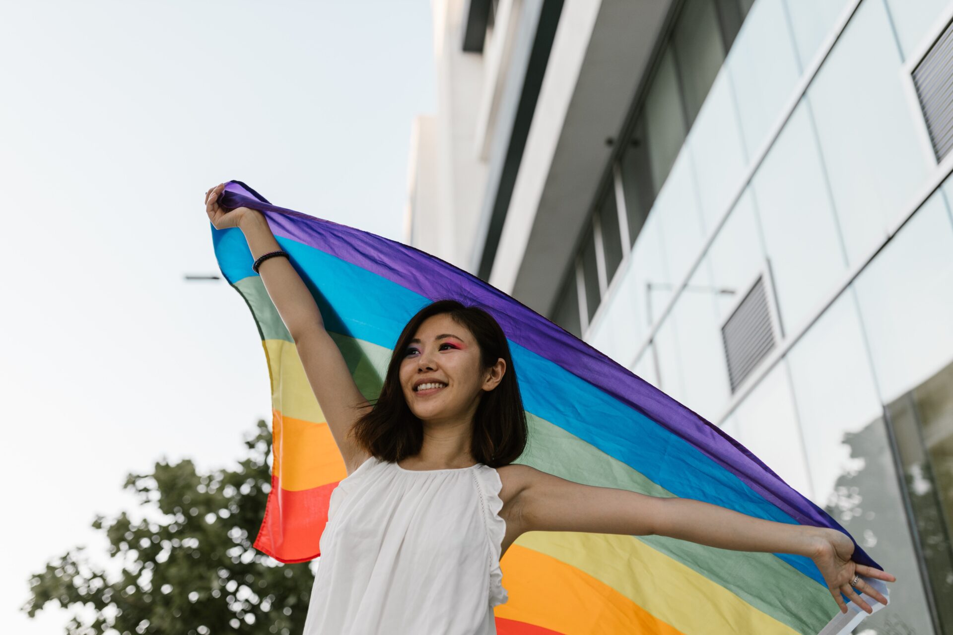 A woman smiling and holding up a Pride flag.