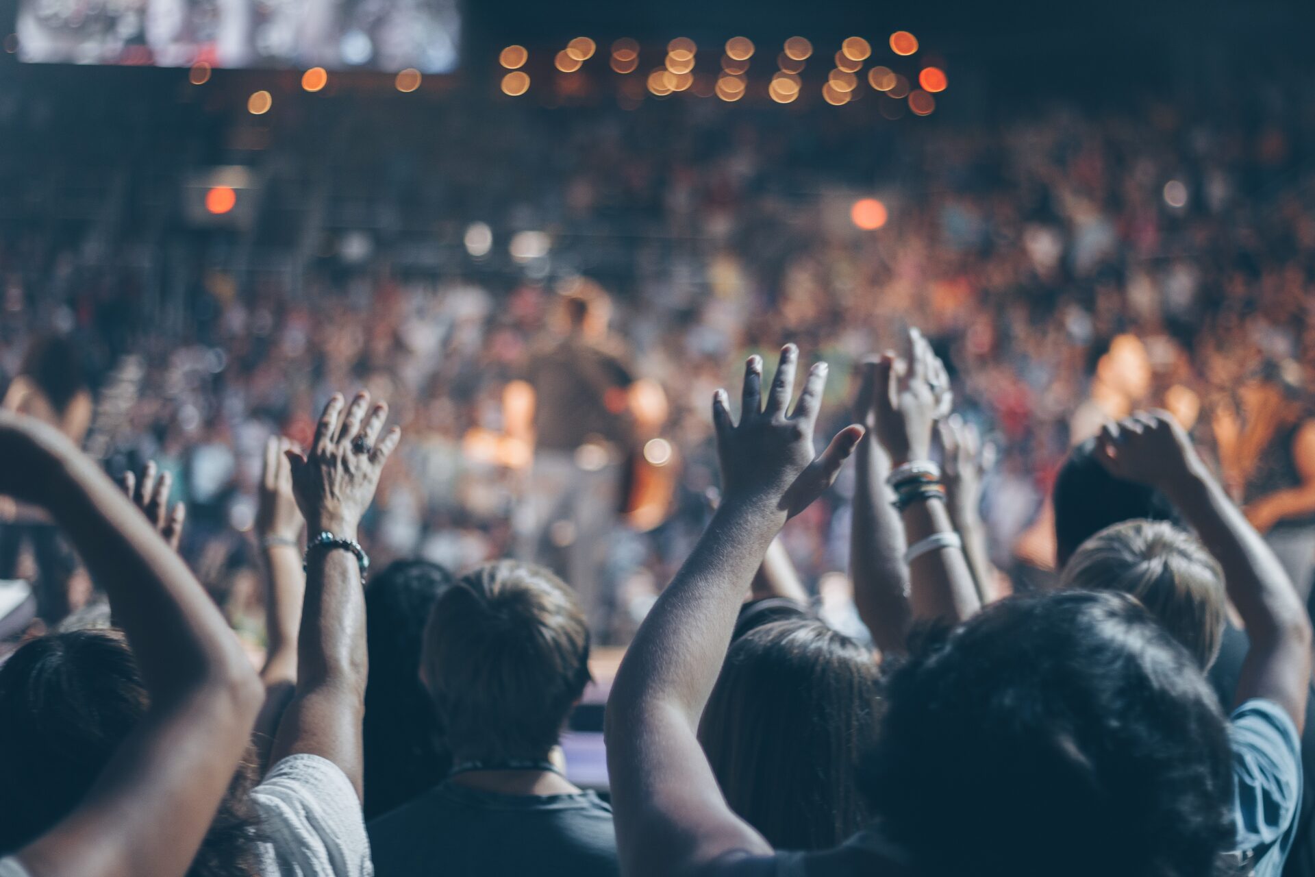 A crowd of people with their hands in the air at a concert.