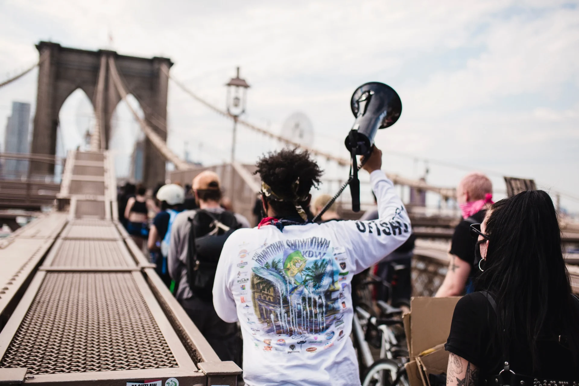 People marching across a bridge with signs and a megaphone in hand, relating to an article about sustained activism.